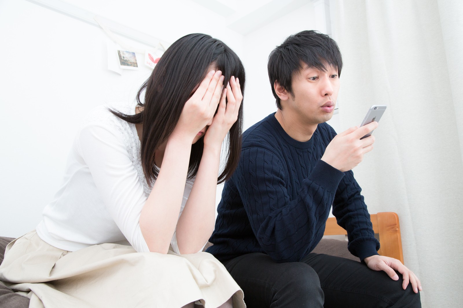 泣く女性とスマホをいじる男性